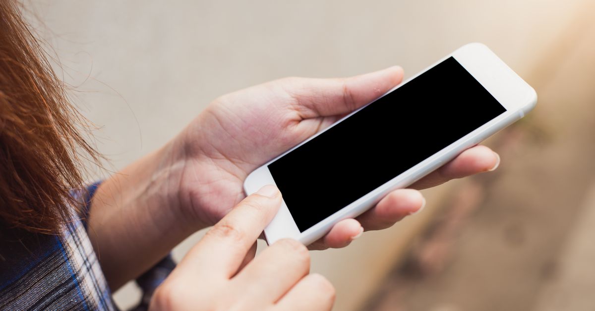 Person holding and using a smartphone outdoors, focusing on hands and screen.